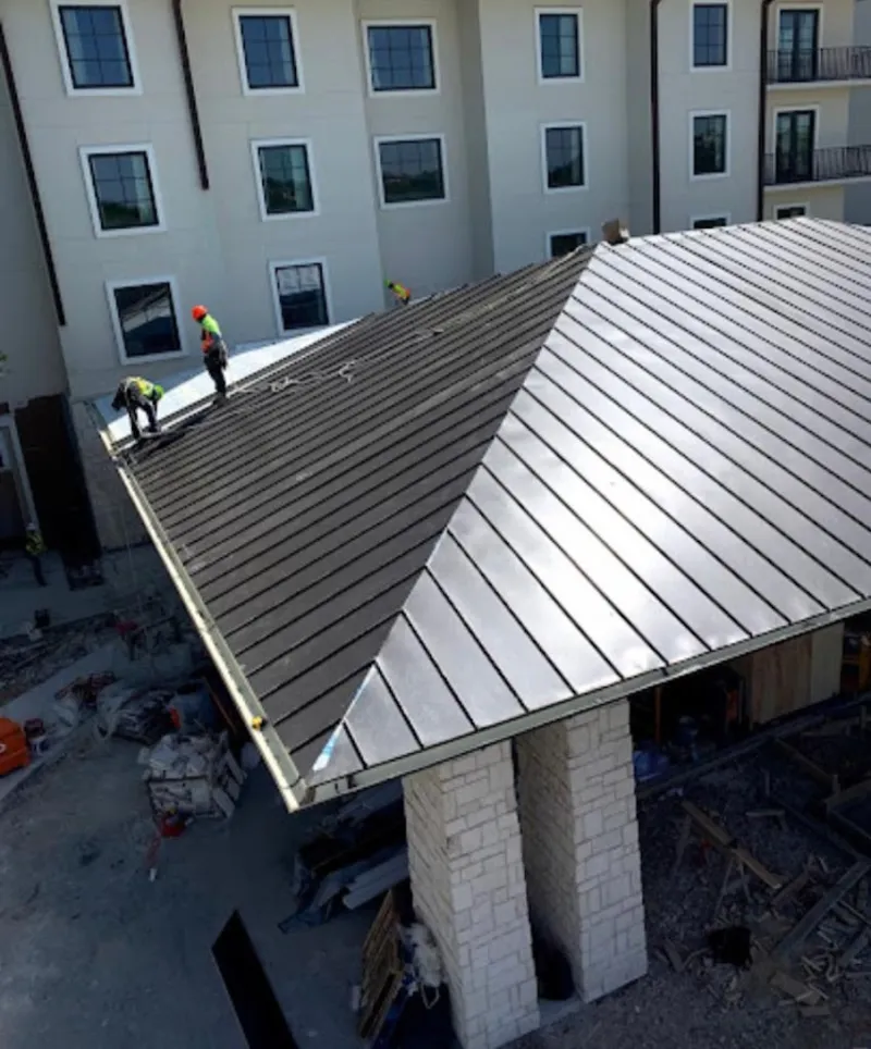 Crew installing standing seam metal roof panels on a commercial project in McKinney